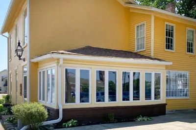 a conservatory on the side of a yellow house at Historic Troy Home Close to Shops with Fire Pit in Troy