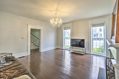 an empty living room with a fireplace and a chandelier at Historic Troy Home Close to Shops with Fire Pit in Troy