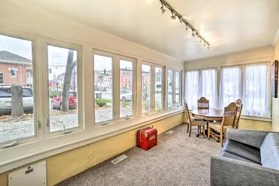 a living room with a table and a bunch of windows at Historic Troy Home Close to Shops with Fire Pit in Troy
