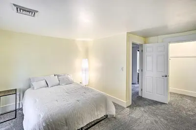 a white bedroom with a bed and a door at Historic Troy Home Close to Shops with Fire Pit in Troy