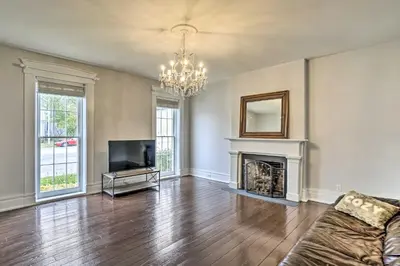 an empty living room with a fireplace and a television at Historic Troy Home Close to Shops with Fire Pit in Troy