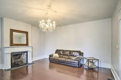 a living room with a leather couch and a chandelier at Historic Troy Home Close to Shops with Fire Pit in Troy