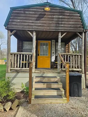 a small cabin with a yellow door and stairs at Acorn Cottage at Hocking Vacations in Logan