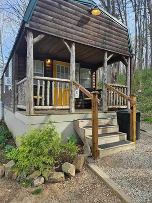 a log cabin with stairs and a porch at Acorn Cottage at Hocking Vacations in Logan
