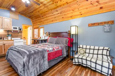 a bedroom with a bed and a chair in a kitchen at Acorn Cottage at Hocking Vacations in Logan