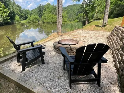 a patio with two chairs and a table next to a lake at The Hideaway on Tacketts - Shipping Container in Hurricane