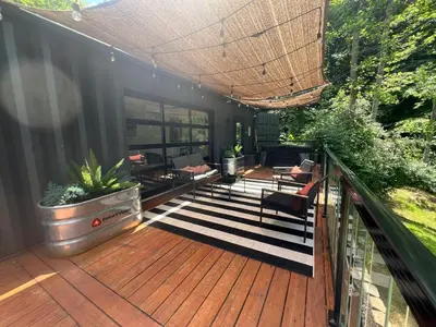 a patio with a deck with furniture and a roof at The Hideaway on Tacketts - Shipping Container in Hurricane