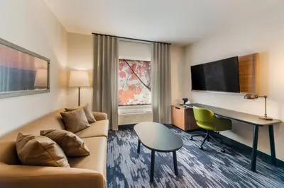 a hotel room with a couch and a desk and a table at Fairfield by Marriott Inn & Suites Columbus Canal Winchester in Canal Winchester