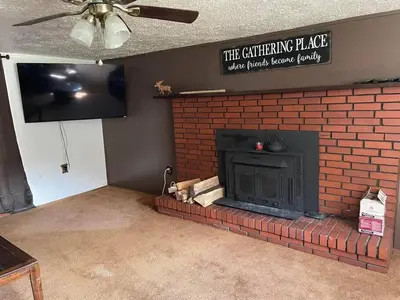 a living room with a brick fireplace and a tv at Sheppard's Holler in Parsley