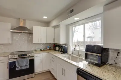 a kitchen with white cabinets and a sink and a window at Spacious Lakefront House with Backyard Fire Pit in Monroe