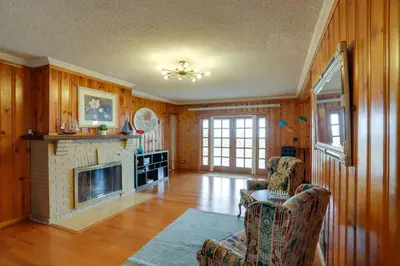 a living room with a fireplace and wooden walls at Spacious Lakefront House with Backyard Fire Pit in Monroe