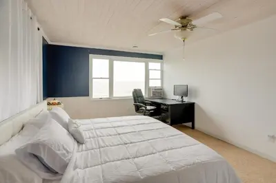 a bedroom with a large white bed and a desk at Spacious Lakefront House with Backyard Fire Pit in Monroe