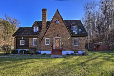 a brick house with a chimney on a lawn at Half-Mi to Dawkins Rail Trail Family Home with Yard in Paintsville