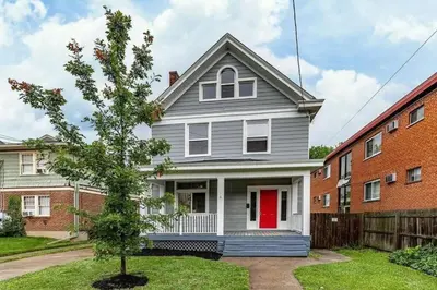 a gray house with a red door in a yard at 6 BR Home Just Minutes From Downtown Cincinnati in Cincinnati