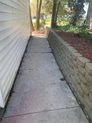 a sidewalk next to a brick wall next to a house at Comfortable Two Bedroom on Royal in Springboro in Springboro