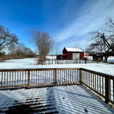 a snow covered bridge with a fence and a barn at Remodeled Farm House with Plenty of Charm in Monroe