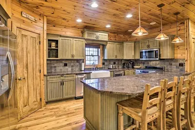 a kitchen with wooden cabinets and a large island with chairs at Walhonding Woods Secluded Farmland Retreat! in Walhonding