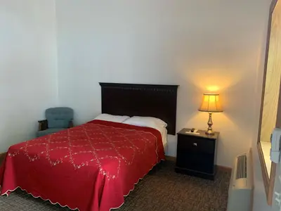 a bedroom with a bed with a red blanket and a lamp at HAVEN INN in Glendale