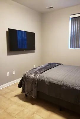a bedroom with a bed and a flat screen tv on the wall at Fresh Modern Industrial split level in Cincinnati