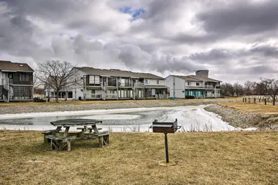 a picnic table and a grill in front of houses at Condo with Balcony, Dock and Access to Lake Erie in Sand Beach