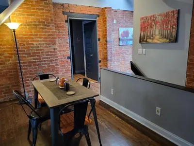 a table and chairs in a room with a brick wall at Modern Rustic split level with balcony in Cincinnati