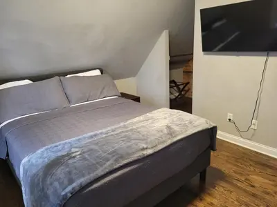 a bedroom with a bed and a flat screen tv at Modern Rustic split level with balcony in Cincinnati