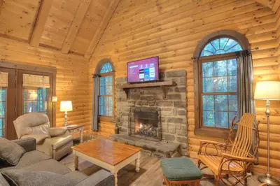 a living room with a fireplace in a log cabin at Apple Blossom Cabin by Amish Country Lodging in Millersburg