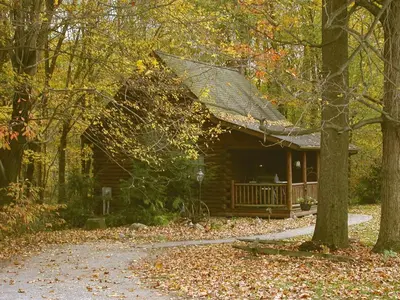 a log cabin with a porch in the woods at Apple Blossom Cabin by Amish Country Lodging in Millersburg