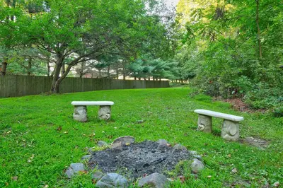 two stone benches sitting in the grass in a park at Apple Blossom Cabin by Amish Country Lodging in Millersburg