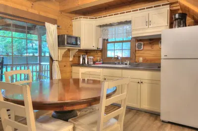 a kitchen with a wooden table and a refrigerator at Apple Blossom Cabin by Amish Country Lodging in Millersburg