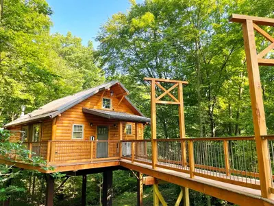 a tree house in the woods with a bridge at Cricket Hill Treehouse D by Amish Country Lodging in Millersburg