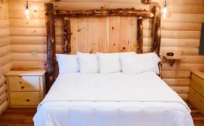 a bedroom with a white bed in a log cabin at Cricket Hill Treehouse D by Amish Country Lodging in Millersburg
