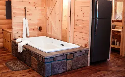 a bath tub in a room with a refrigerator at Cricket Hill Treehouse D by Amish Country Lodging in Millersburg