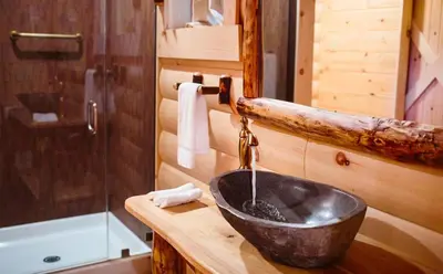 a bathroom with a sink in a log cabin at Cricket Hill Treehouse D by Amish Country Lodging in Millersburg