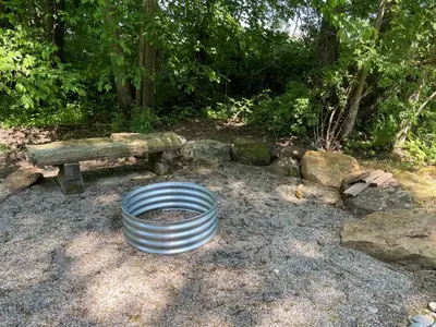 a metal barrel sitting in front of a bench at Cricket Hill Treehouse D by Amish Country Lodging in Millersburg