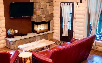 a living room with red leather chairs and a fireplace at Cricket Hill Treehouse C by Amish Country Lodging in Millersburg