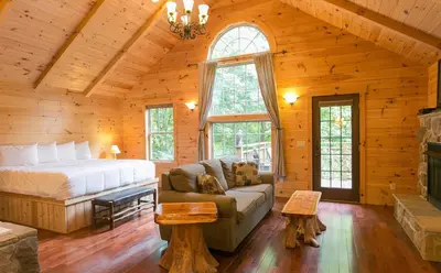 a bedroom in a log cabin with a bed and a couch at Lofty Willows Treehouse by Amish Country Lodging in Millersburg