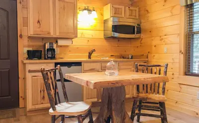 a kitchen with a table and chairs in a cabin at Lofty Willows Treehouse by Amish Country Lodging in Millersburg