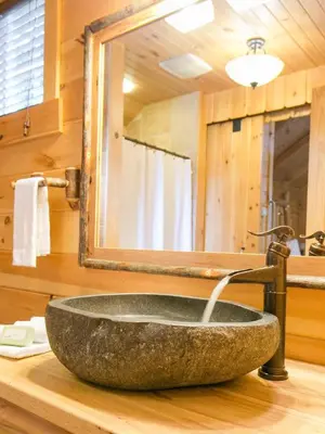 a stone sink in a bathroom with a mirror at Lofty Willows Treehouse by Amish Country Lodging in Millersburg