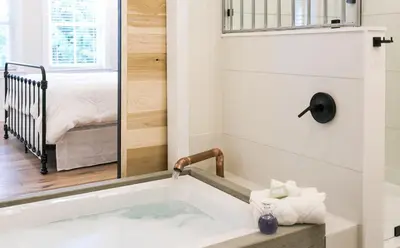 a bathtub in a bathroom with a bedroom at Farmhouse Suites by Amish Country Lodging in Millersburg