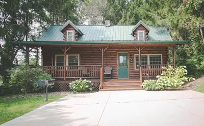 a log cabin with a porch and a green door at Evergreen Cabin by Amish Country Lodging in Millersburg
