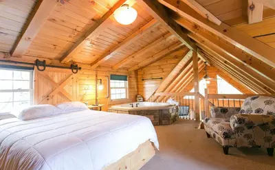 a bedroom with a bed and a tub in a cabin at Evergreen Cabin by Amish Country Lodging in Millersburg