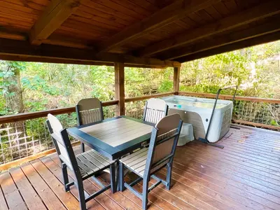 a deck with a table and chairs and a hot tub at Evergreen Cabin by Amish Country Lodging in Millersburg