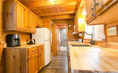 a kitchen with wooden cabinets and a white refrigerator at Evergreen Cabin by Amish Country Lodging in Millersburg