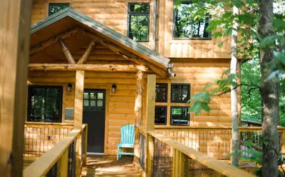 a log cabin with a porch and a door at Treehouse #1 by Amish Country Lodging in Millersburg