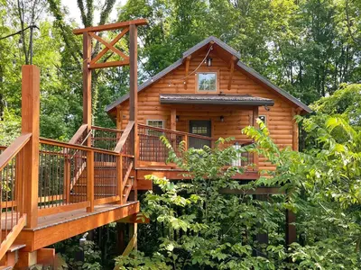 a cabin in the woods with a large deck at Treehouse #0 by Amish Country Lodging in Millersburg