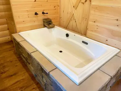 a large white tub in a room with wooden walls at Treehouse #0 by Amish Country Lodging in Millersburg