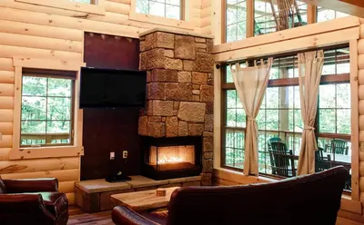 a living room with a stone fireplace and a tv at Treehouse #2 by Amish Country Lodging in Millersburg