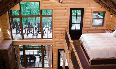 a bedroom in a log cabin with a bed and a balcony at Treehouse #2 by Amish Country Lodging in Millersburg