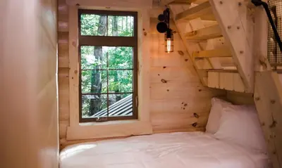 a bed in a tiny house with a window at Treehouse #3 by Amish Country Lodging in Millersburg
